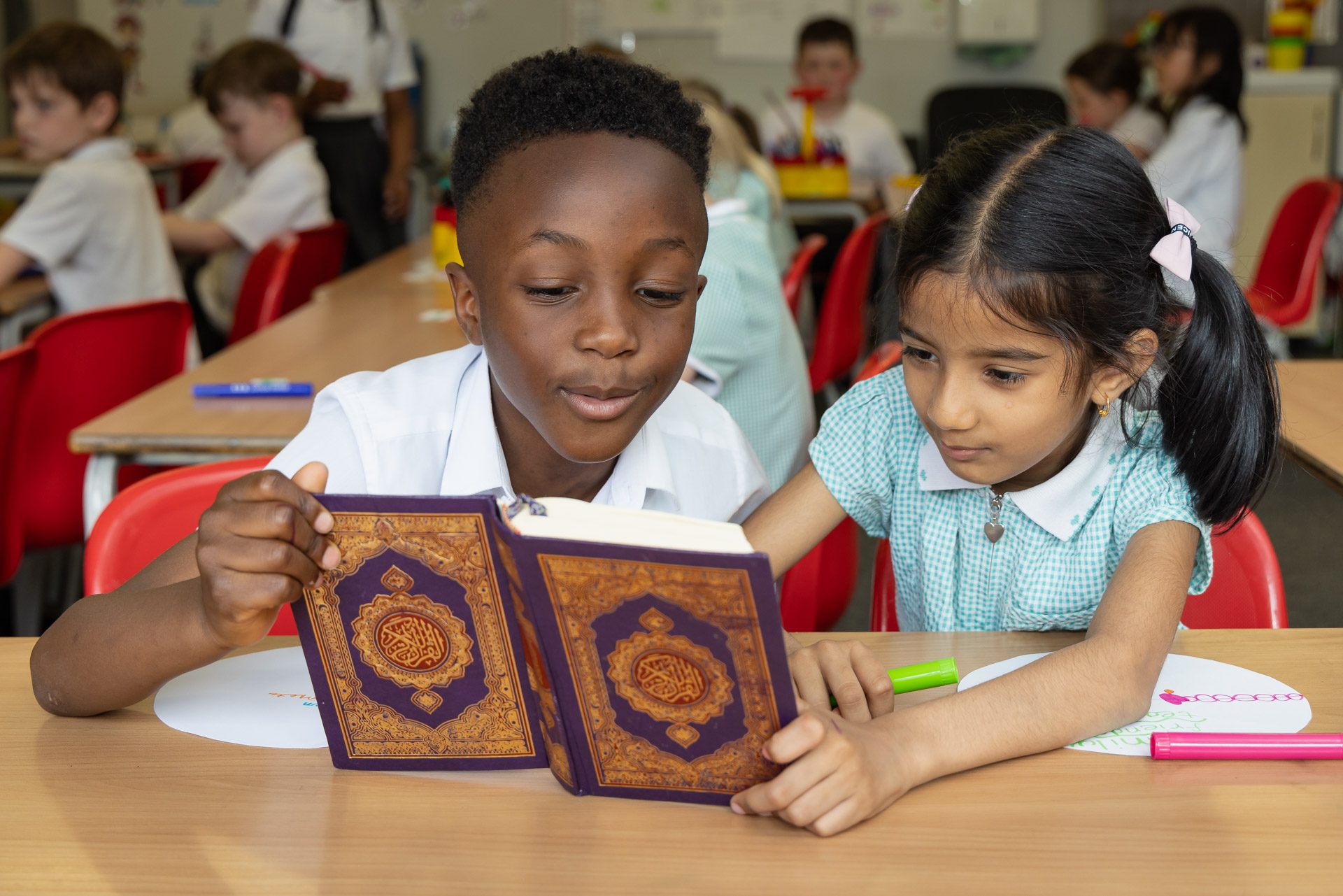 a boy and a girl reading from the Quran